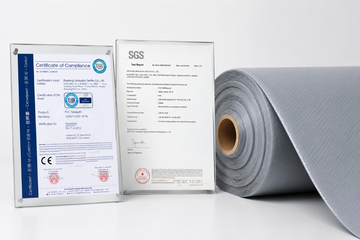 Certification documents displayed alongside a roll of anti-static heavy-duty PVC fabric