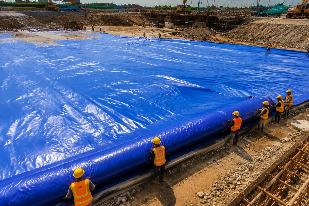 Custom sized PVC tarpaulin being unrolled over a large construction site