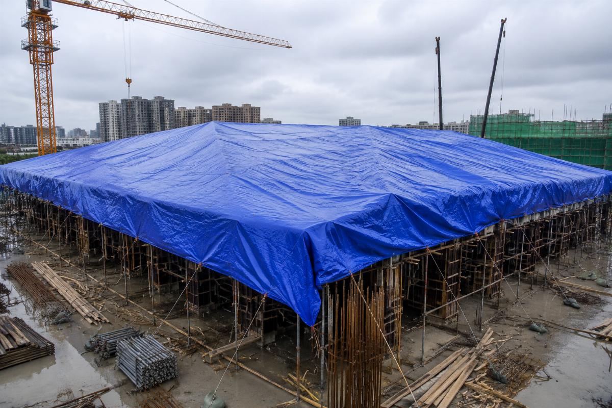 Heavy-duty PVC tarpaulin laid over a construction site as temporary roof cover
