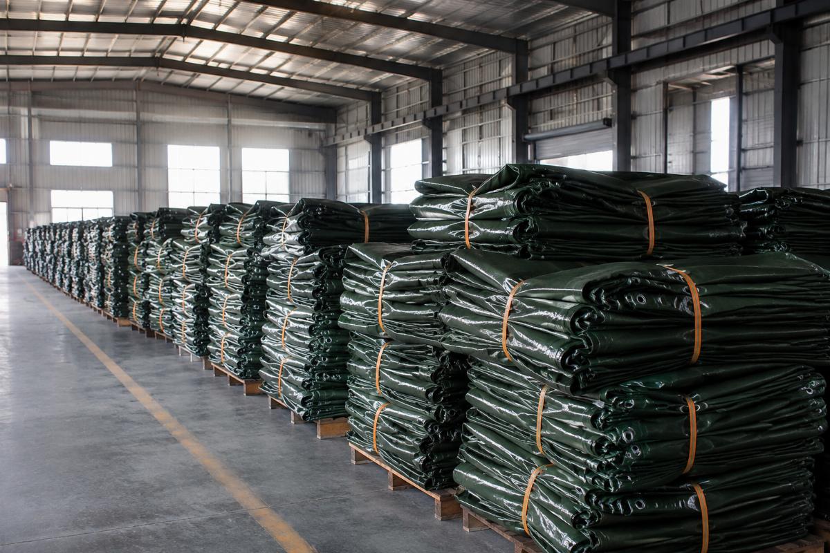 Warehouse of finished hay cover tarps ready for shipment from a Chinese industrial fabric factory